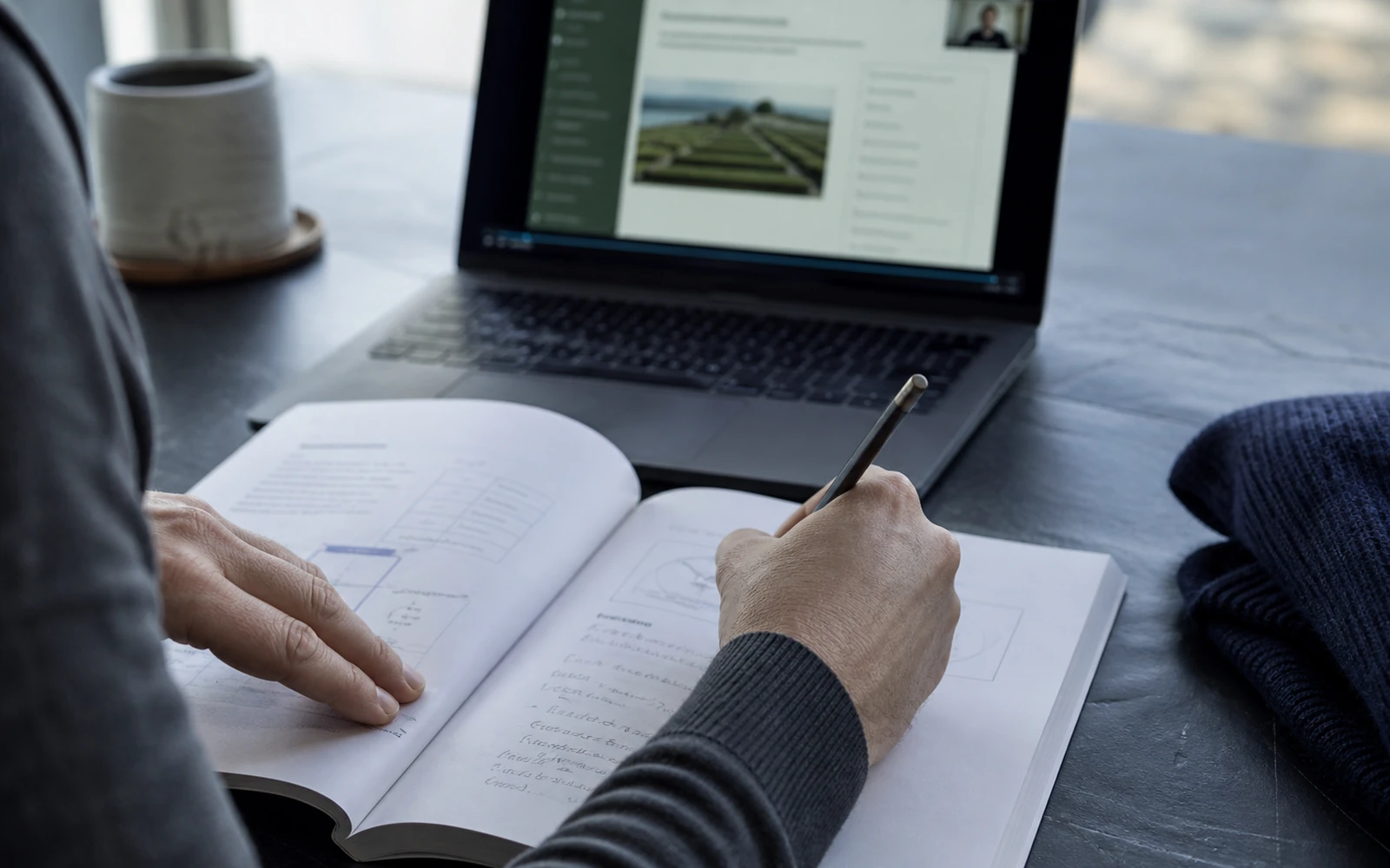 A desk with a course slide on screen and an open workbook beside it